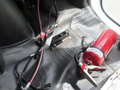 A fire extinguisher secured on the floor of a 2020 Chevrolet Express with wiring and brackets visible around it