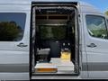 A 2017 Mercedes-Benz Sprinter with an open side door revealing an interior that includes seats and a wooden storage box
