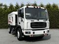 A 2012 Autocar Xpert street sweeper with a white and red body featuring a large front grille and headlights along with a broom attachment at the front