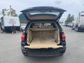 The interior of a 2009 BMW X5 with the rear hatch open revealing a spacious cargo area and beige upholstery
