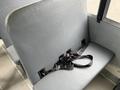 A gray bus seat with a black seatbelt secured to it