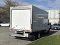 A 2023 Ford E-450 box truck with a white cargo area and rear loading door parked on a grassy area