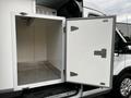 A 2025 Ford Transit with an open side door revealing a spacious, empty storage compartment featuring metal shelves and a clean interior