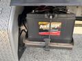 A close-up of a PowrSurge battery mounted on a bracket within a Freightliner M2 106 truck with a textured metal backdrop