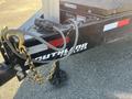 A 2024 Southland 18 Foot Dump Trailer with a chain and hook attached to the hitch and a hydraulic line connected on the side