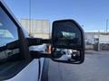 A 2020 Ford F-550 side mirror reflecting a nearby object and showcasing its black frame and dual mirror design