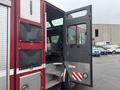 A 2006 E-One Typhoon emergency vehicle with a red exterior and visible access door open, showcasing the interior seating and equipment area