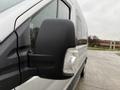 Close-up of the side mirror and blinker light on a 2019 Ford Transit van with rain droplets on the surface