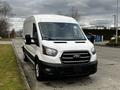 A white 2020 Ford Transit van is parked with its front view visible showcasing a black grille and headlights