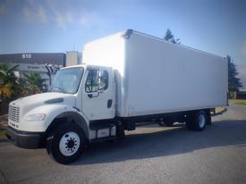 A 2016 Freightliner M2 106 Medium Duty truck with a white box cargo area and black wheels parked on a street