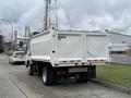 A 2014 Hino 195 truck with a white dump bed and a grey cab parked on a concrete surface