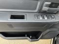 The interior door panel of a 2015 RAM 1500 featuring a control panel with window lift buttons and a storage compartment below