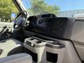 Interior view of a 2013 Ford Econoline with gray upholstery featuring a dashboard with controls and a console with cup holders