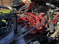 Close-up of the engine components of a 2012 Freightliner M2 112 showing red-painted parts along with various hoses and wiring configurations