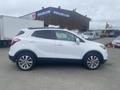 A white 2018 Buick Encore SUV parked, featuring a sleek design with alloy wheels and black trim around the windows and wheel arches