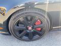 A black wheel of a 2015 Bentley Continental GT featuring a shiny spoke design and red brake calipers with the Bentley logo in the center