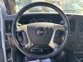 Steering wheel of a 2019 GMC Savana featuring the GMC logo buttons for audio and cruise control on the sides and a digital display panel in the background