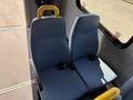 Two blue padded seats with yellow seat backs and seat belts positioned in a vehicle cabin