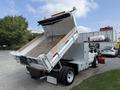 A 2007 Ford F-450 dump truck with its bed raised for unloading materials