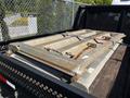 A metal loading ramp secured with chains on the back of a truck, featuring a smooth surface and angled edges for easy access