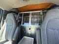 Interior of a 2007 Chevrolet Express showing two front seats and a metal partition with a grid separating the front and back areas