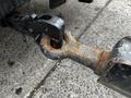 A close-up of a rusted hitch attachment on a trailer showing a heavy-duty metal connection point and a safety chain clip