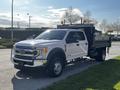A 2021 Ford F-550 truck with a flatbed in front view featuring side mirrors and light bars on the roof.
