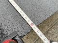 A close-up of a tape measure laying on a wet surface with water droplets visible on the tape and surface