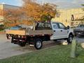 A 2018 Ford F-350 SD flatbed truck in white parked with a wooden bed and black accents