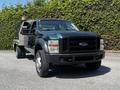 A 2008 Ford F-550 with a black body and large tires featuring an open utility bed on the back equipped with a toolbox and additional storage compartments