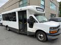 A 2017 Chevrolet Express bus with a white exterior and a large front windshield has multiple passenger windows and a raised front section for added height