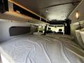 Interior of a 2017 Mercedes-Benz Sprinter with a cozy bed made up in the back featuring pillows and bedding arranged neatly