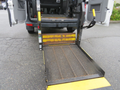 A 2009 Dodge Sprinter Van with a lowered wheelchair ramp extended from the rear entrance showing a metal mesh surface and yellow safety stripes