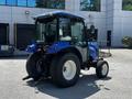 A 2018 New Holland Boomer 45 tractor with a blue body and large rear tires positioned prominently with a closed cab and a rear attachment