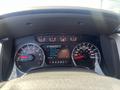 Dashboard of a 2014 Ford F-150 showing speedometer tachometer and a digital display with fuel economy information and truck apps settings