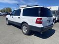 A white 2013 Ford Expedition with black lower panels parked with its rear facing the viewer and no visible license plate