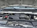 Engine compartment of a 2009 Ford Econoline showing various components including the air intake hose battery and fluid reservoirs