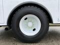 A close-up of a large black tire mounted on a white wheel with bright green lug nuts on a 2005 Freightliner M2 106 vehicle