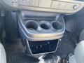 Interior view of a 2012 GMC Savana showing a center console with cup holders and an open storage compartment below