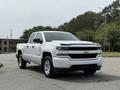 A white 2018 Chevrolet Silverado 1500 pickup truck is parked with its front angled slightly towards the viewer showcasing its distinctive grille and headlights