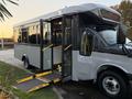 A 2019 Chevrolet Express bus with an open door and a wheelchair ramp extended from the rear entrance