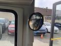 A circular side mirror mounted inside a vehicle reflecting the interior of a 2018 Chevrolet Express and cars parked outside