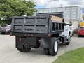 A 2017 Ford F-750 dump truck with a raised bed and wooden planks in the cargo area, viewed from the rear