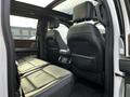 Interior view of a 2021 Ford F-150 showing two black leather front seats and a panoramic sunroof with a console between the seats