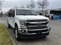 A white 2020 Ford F-350 Super Duty truck is parked with a large front grille and chrome accents