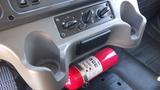 A red fire extinguisher secured in a compartment of a Freightliner M2 106 truck's interior cabinetry