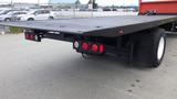 A 2015 International DuraStar 4300 flatbed truck with a black cargo area and red rear lights