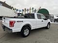 A white 2017 Ford F-150 with a crew cab and 4x4 badge parked on a concrete surface