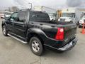 A black 2004 Ford Explorer Sport Trac with a pickup truck bed and chrome side steps visible from the rear angle