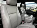 Interior view of a 2016 Ford F-150 with two front seats in light gray leather and a center console with cup holders